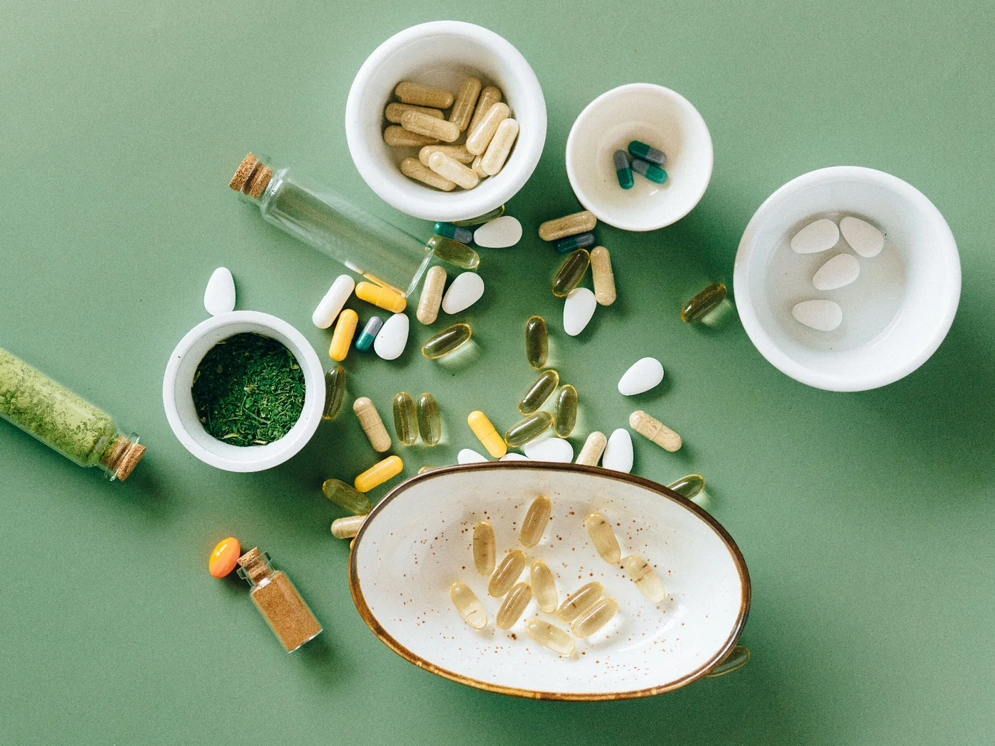 Supplement capsules, softgels and actives in ceramic bowls — GMP blending and encapsulation